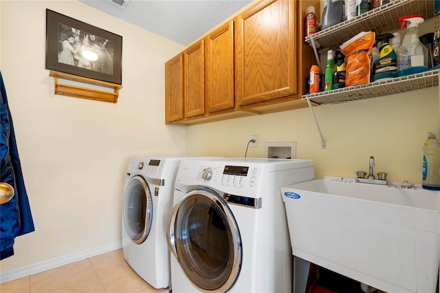 laundry area featuring washing machine and dryer, cabinet space, a sink, and light tile patterned floors