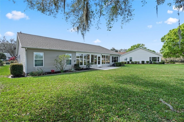 back of property featuring roof with shingles, a yard, and a patio