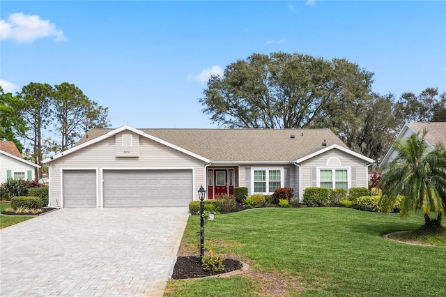 single story home with an attached garage, decorative driveway, and a front yard