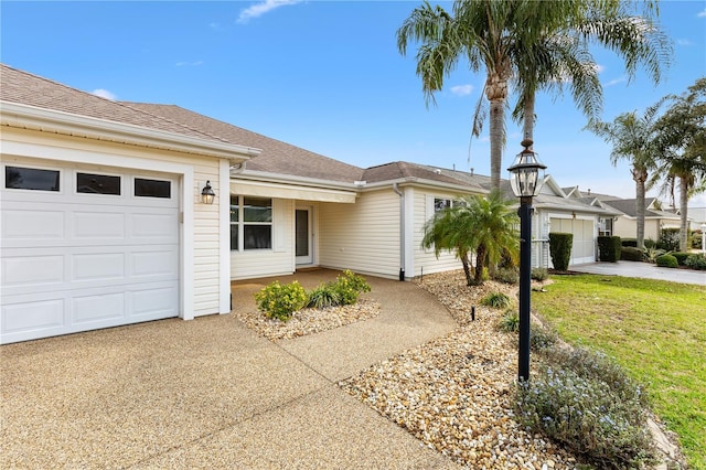 ranch-style house featuring a garage, a front yard, concrete driveway, and roof with shingles