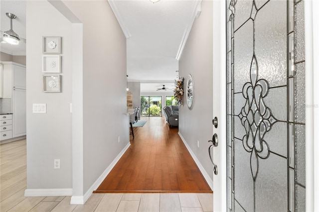 foyer entrance featuring ornamental molding, baseboards, light wood finished floors, and a ceiling fan