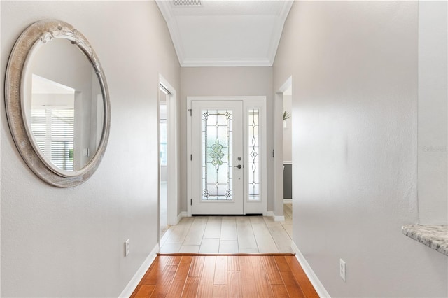 foyer with a healthy amount of sunlight, light wood finished floors, baseboards, and ornamental molding