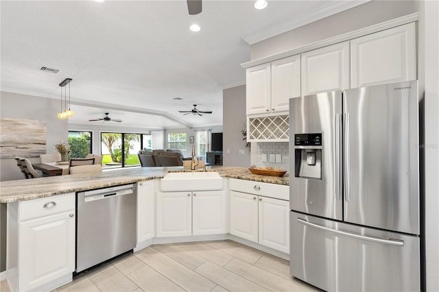 kitchen with a peninsula, a sink, white cabinetry, open floor plan, and appliances with stainless steel finishes