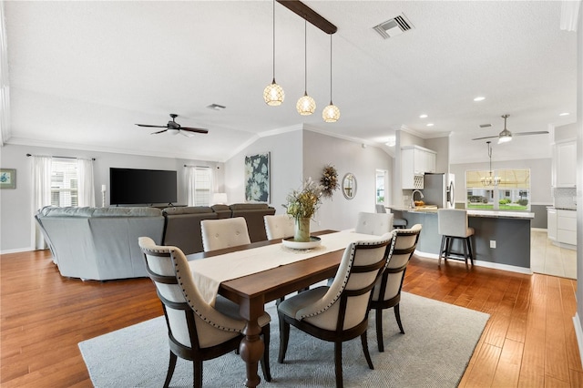 dining space featuring ceiling fan with notable chandelier, wood finished floors, visible vents, baseboards, and crown molding