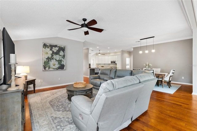 living room with ornamental molding, vaulted ceiling, and wood finished floors