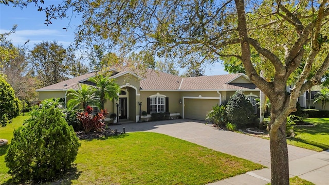 view of front facade with a garage, stucco siding, decorative driveway, and a front yard