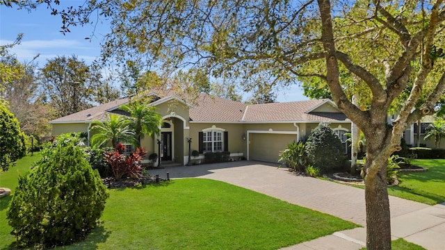 view of front facade featuring a front yard, decorative driveway, a garage, and stucco siding