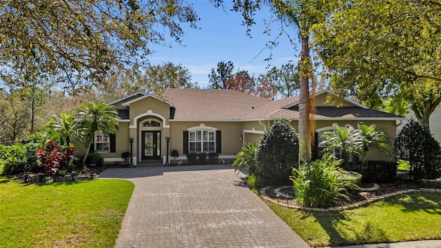 mediterranean / spanish-style house featuring a front lawn, decorative driveway, and stucco siding