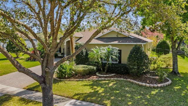 view of front of property featuring a shingled roof, a front yard, and stucco siding