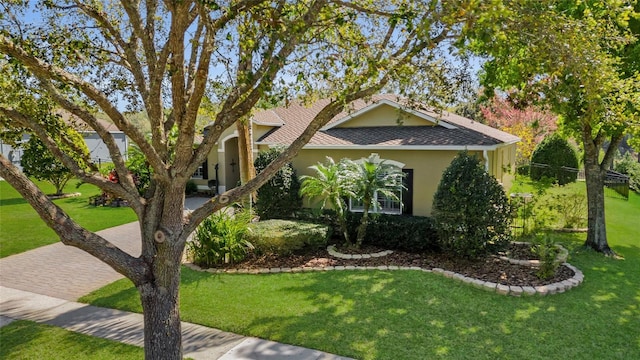 view of front of house with roof with shingles, a front yard, and stucco siding