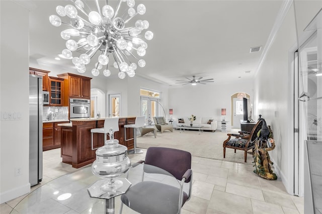 dining room with baseboards, visible vents, arched walkways, crown molding, and ceiling fan with notable chandelier