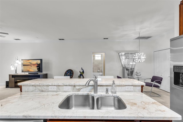 kitchen featuring visible vents, light stone counters, stainless steel refrigerator with ice dispenser, and a sink