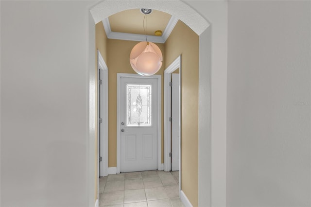 doorway with light tile patterned floors, ornamental molding, arched walkways, and baseboards