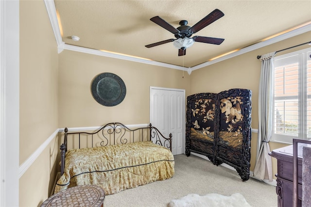 bedroom with ceiling fan, ornamental molding, a textured ceiling, and carpet flooring