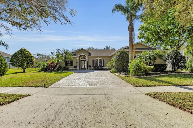 view of front of property featuring decorative driveway, a front lawn, and stucco siding