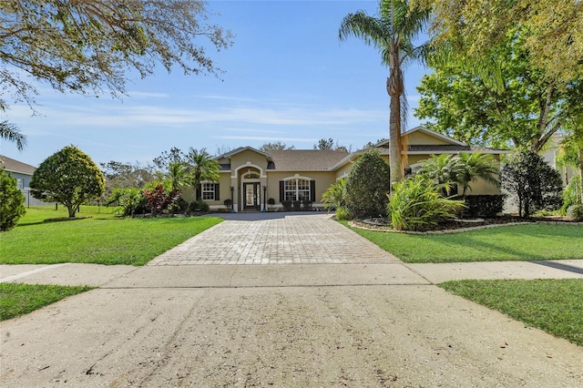 view of front facade with a front lawn, decorative driveway, and stucco siding