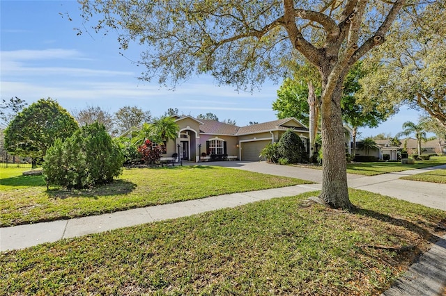 view of front of house with driveway, an attached garage, a front lawn, and stucco siding