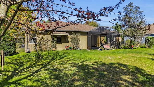 rear view of property with glass enclosure, fence, stucco siding, and a yard