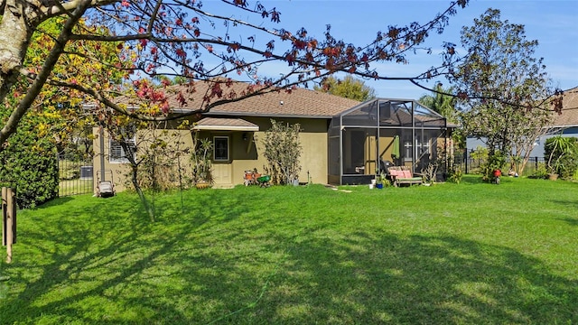 back of house with a lanai, a fenced backyard, a lawn, and stucco siding