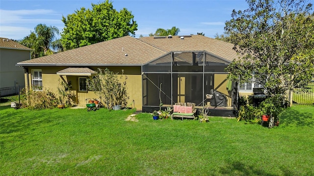 back of property with glass enclosure, fence, a lawn, and stucco siding