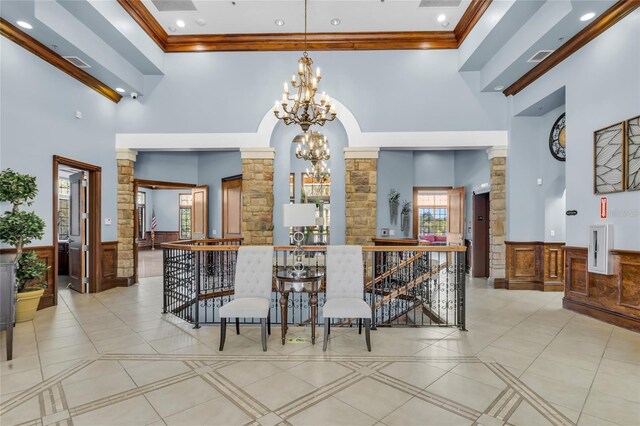 interior space with crown molding, wainscoting, an inviting chandelier, and ornate columns