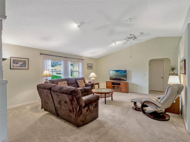 living room featuring arched walkways, vaulted ceiling, a textured ceiling, and light colored carpet