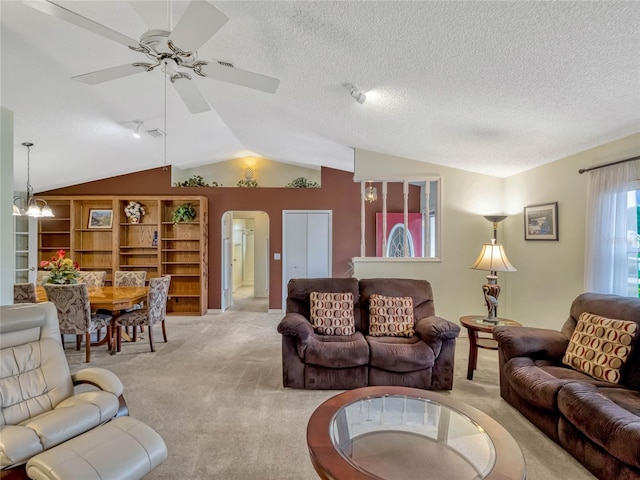 living room featuring arched walkways, lofted ceiling, a textured ceiling, ceiling fan with notable chandelier, and light carpet