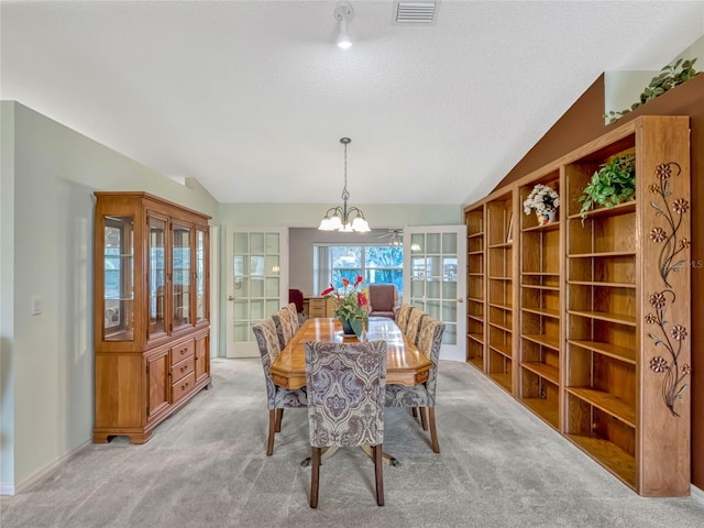 dining area with light carpet, visible vents, lofted ceiling, a textured ceiling, and a notable chandelier