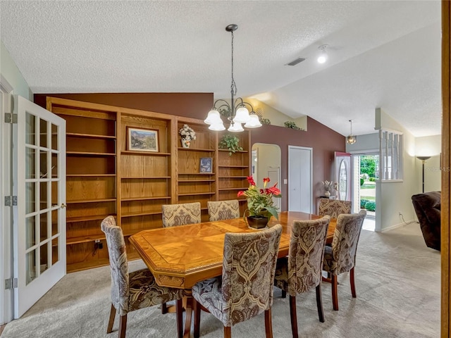 dining room with vaulted ceiling, a textured ceiling, a chandelier, and light colored carpet