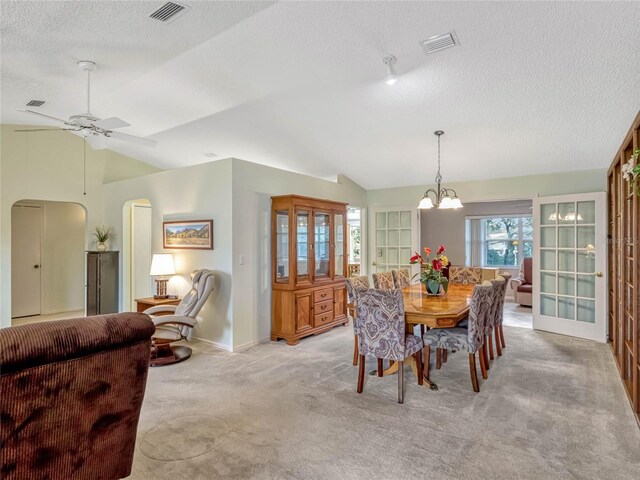 dining area with arched walkways, lofted ceiling, visible vents, and light carpet