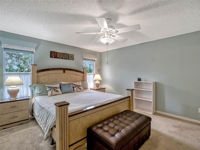 bedroom featuring baseboards, a textured ceiling, a ceiling fan, and light colored carpet