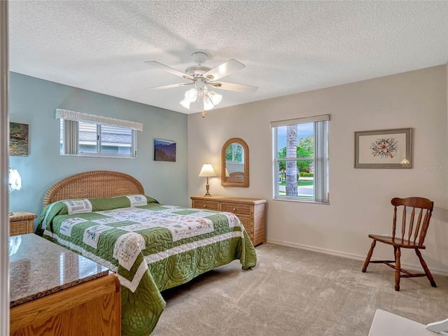 bedroom featuring light colored carpet, a textured ceiling, baseboards, and multiple windows