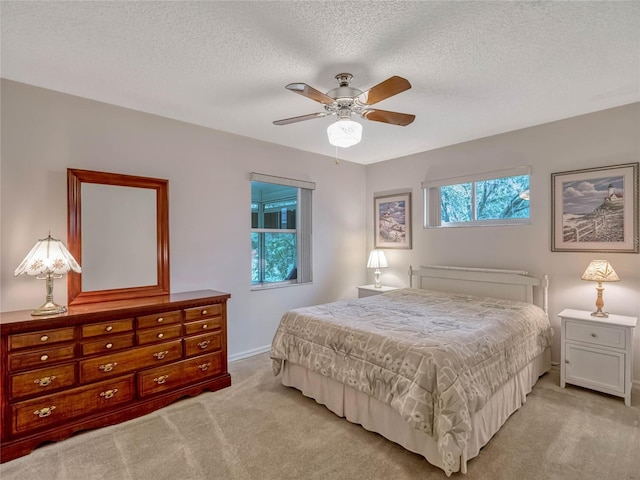 bedroom with light carpet, a textured ceiling, and a ceiling fan