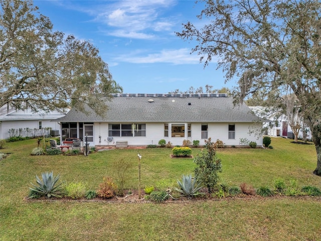 back of house with a yard, a shingled roof, and a sunroom