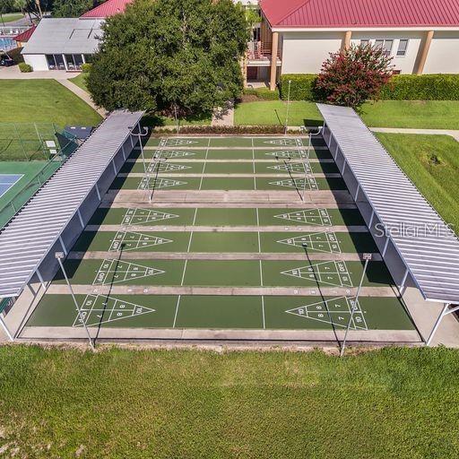 view of home's community with shuffleboard and a lawn