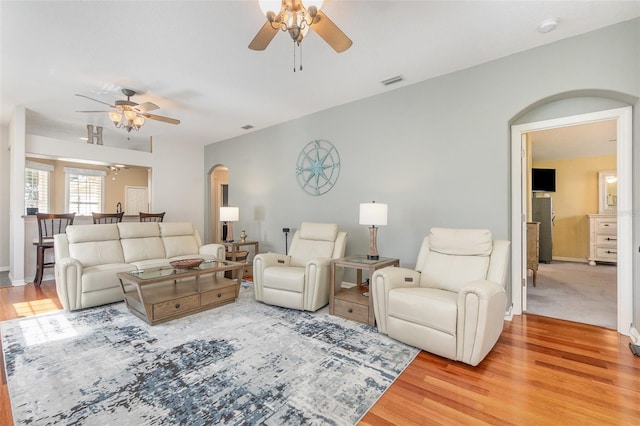 living area featuring arched walkways, wood finished floors, visible vents, and a ceiling fan