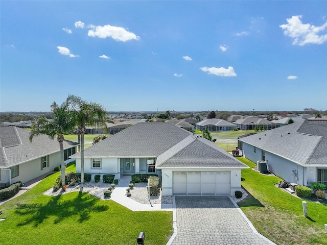 ranch-style home featuring decorative driveway, a front yard, central AC, a garage, and a residential view