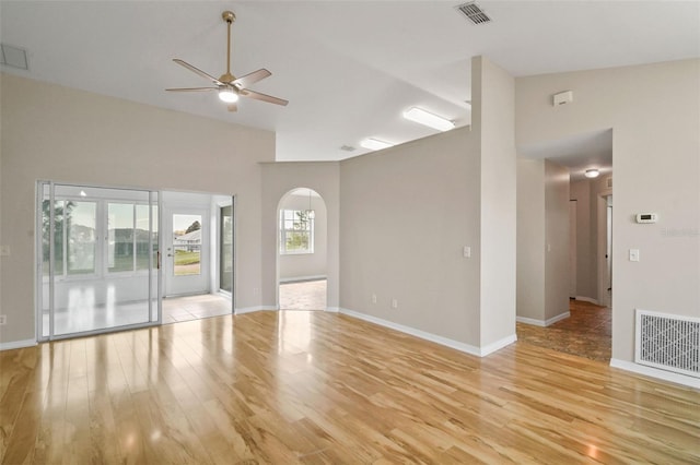 unfurnished living room with arched walkways, visible vents, and light wood finished floors