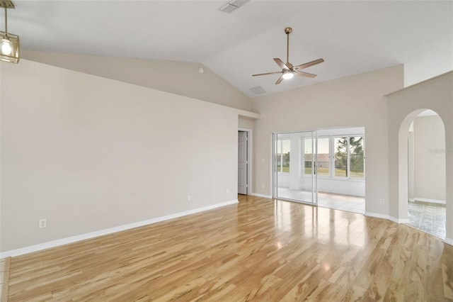 unfurnished room featuring arched walkways, a ceiling fan, visible vents, vaulted ceiling, and light wood-style floors