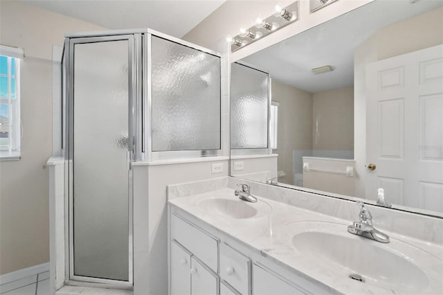 bathroom featuring double vanity, a stall shower, and a sink