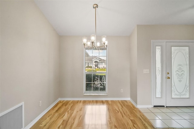 entryway featuring visible vents, a notable chandelier, baseboards, and wood finished floors