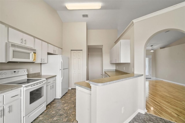 kitchen with white appliances, visible vents, arched walkways, baseboards, and white cabinetry