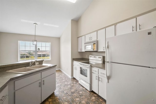 kitchen with white appliances, dark countertops, a sink, and white cabinetry