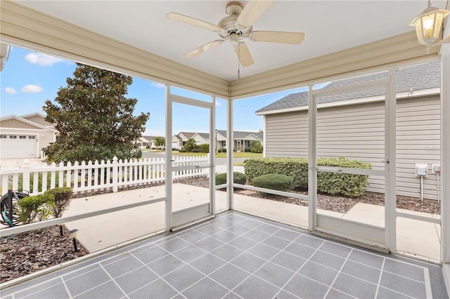 unfurnished sunroom with plenty of natural light, a residential view, and a ceiling fan