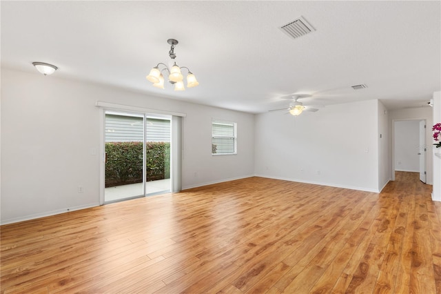 empty room featuring light wood-style flooring, visible vents, baseboards, and ceiling fan with notable chandelier