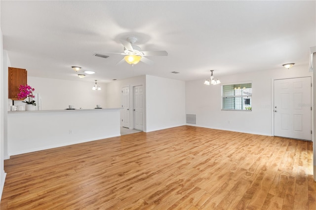 unfurnished living room featuring light wood-style floors, baseboards, visible vents, and ceiling fan with notable chandelier