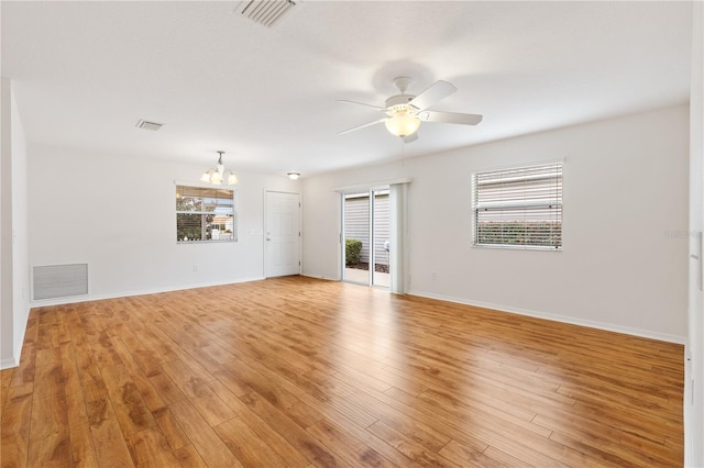 empty room featuring light wood-type flooring, visible vents, and ceiling fan with notable chandelier