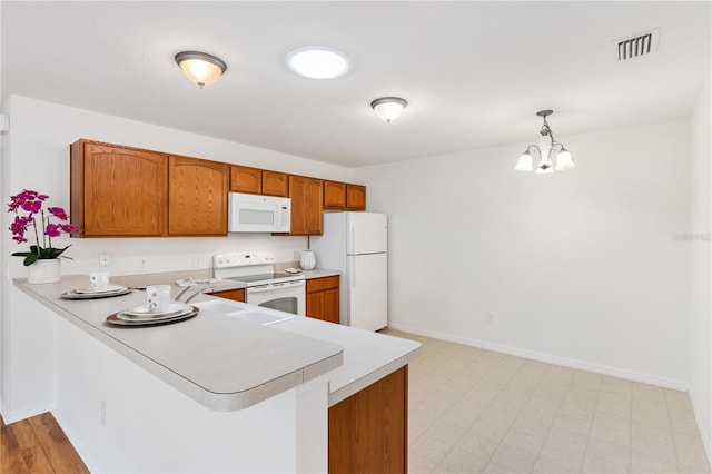 kitchen with white appliances, light countertops, hanging light fixtures, and a peninsula