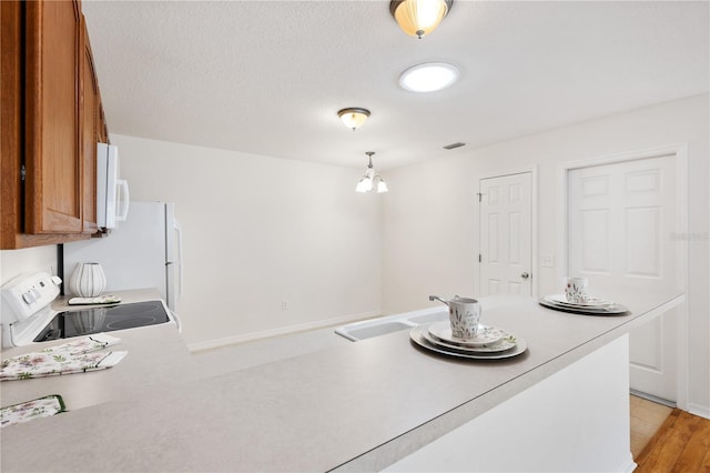 kitchen featuring brown cabinets, white appliances, light countertops, and a sink