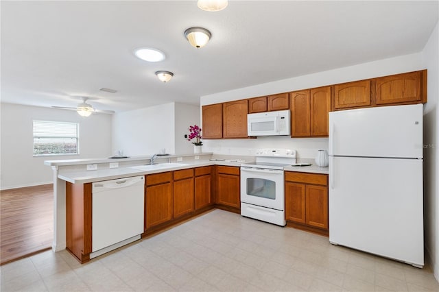 kitchen featuring brown cabinets, light floors, light countertops, white appliances, and a peninsula